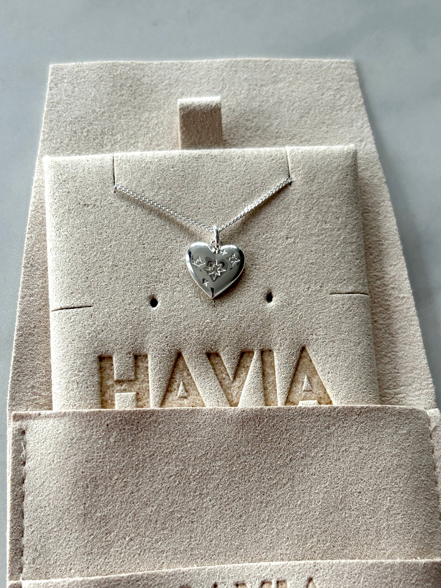 Jewelry set with heart-shaped pendant and earrings in Havia packaging on a marble surface
